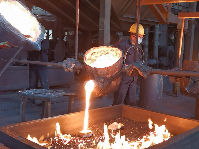 Workers operate ladle for metal casting production