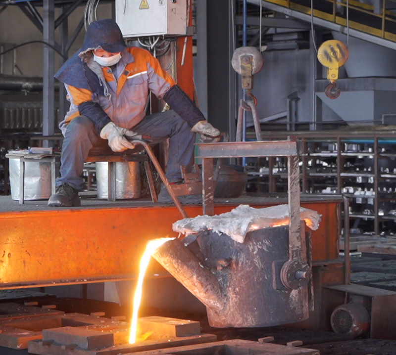 Worker pouring molten metal in casting workshop