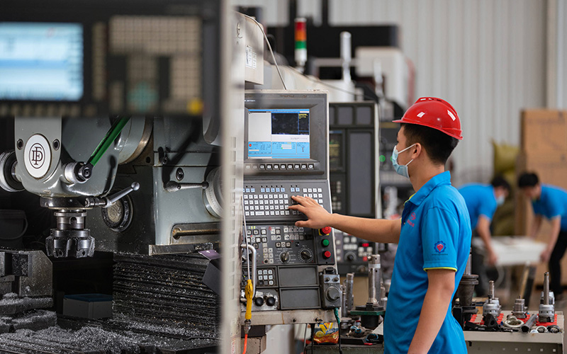 Worker operating CNC machining equipment in workshop